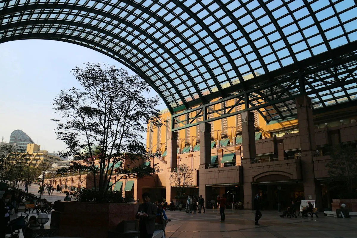 The glass-roofed arcade at Yebisu Garden Place in Ebisu, with red-brick buildings and a tree in the plaza