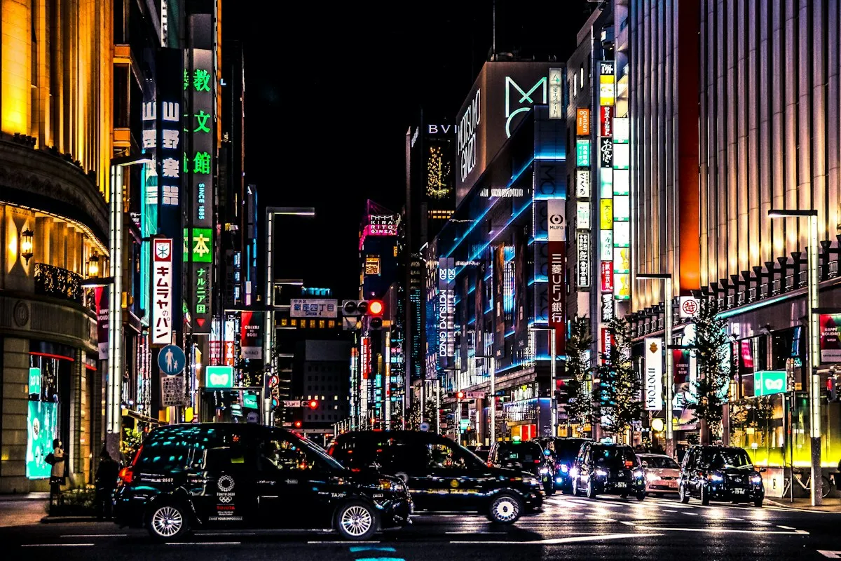 夜の銀座の通りを走るタクシーと車。両側に明るく照らされた店の外観