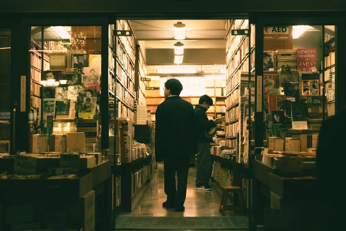 Customers browsing inside a brightly lit Jimbocho bookshop at night