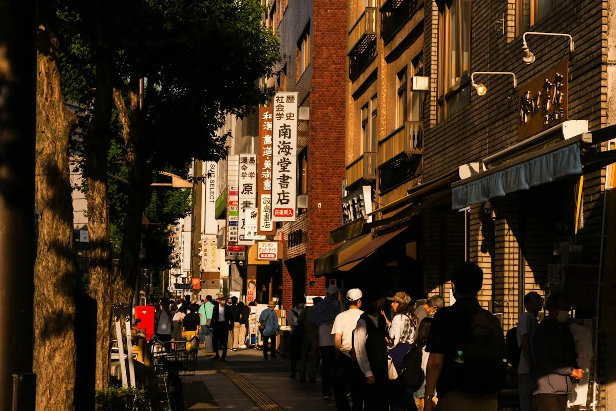 A row of secondhand bookshops along a tree-lined street in Jimbocho in late afternoon light