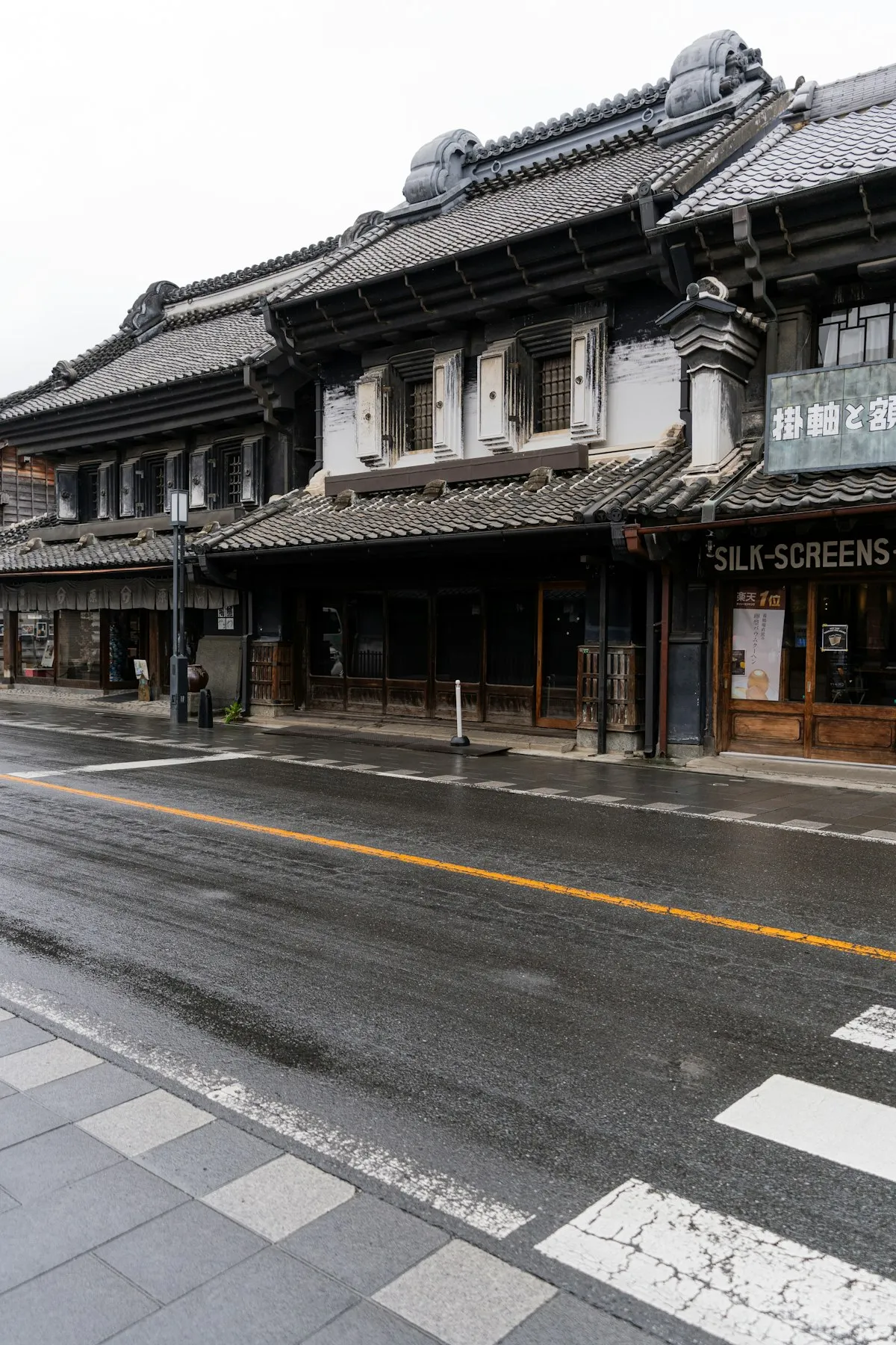 雨に濡れた通りに並ぶ、重厚な瓦屋根の川越の蔵造りの家々