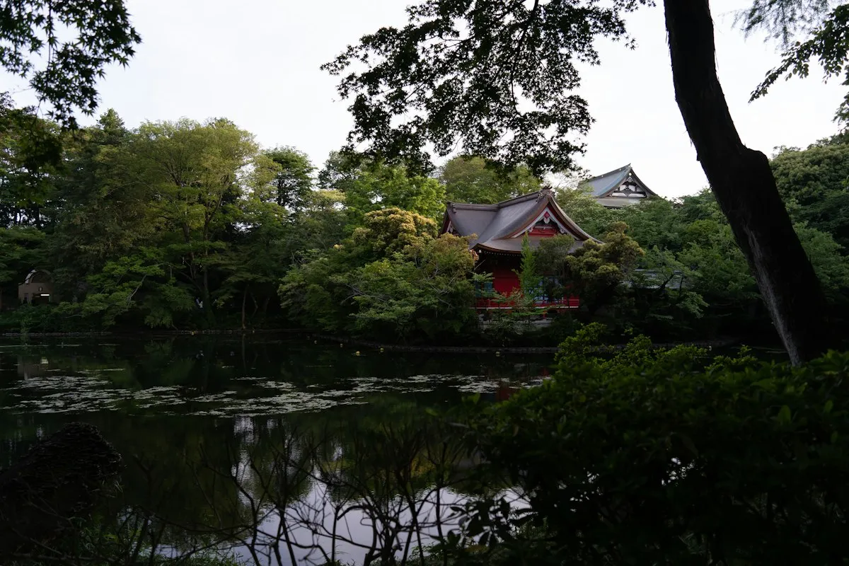 The red Benzaiten shrine on the edge of the pond in Inokashira Park, surrounded by trees