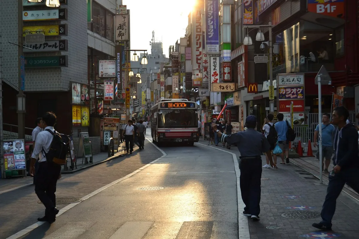 A shopping street near Kichijoji Station in the late afternoon, with a bus and people walking