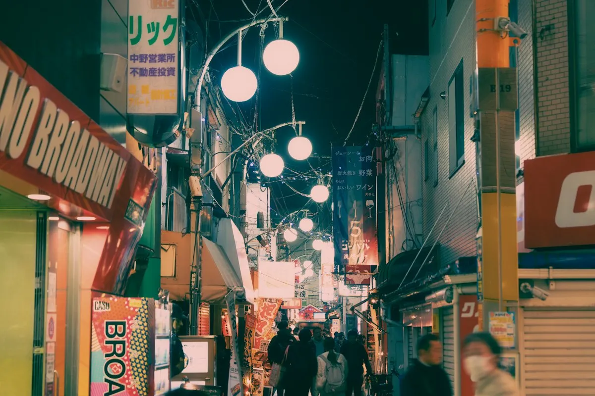 The entrance to Nakano Broadway at night, next to a narrow lit side street