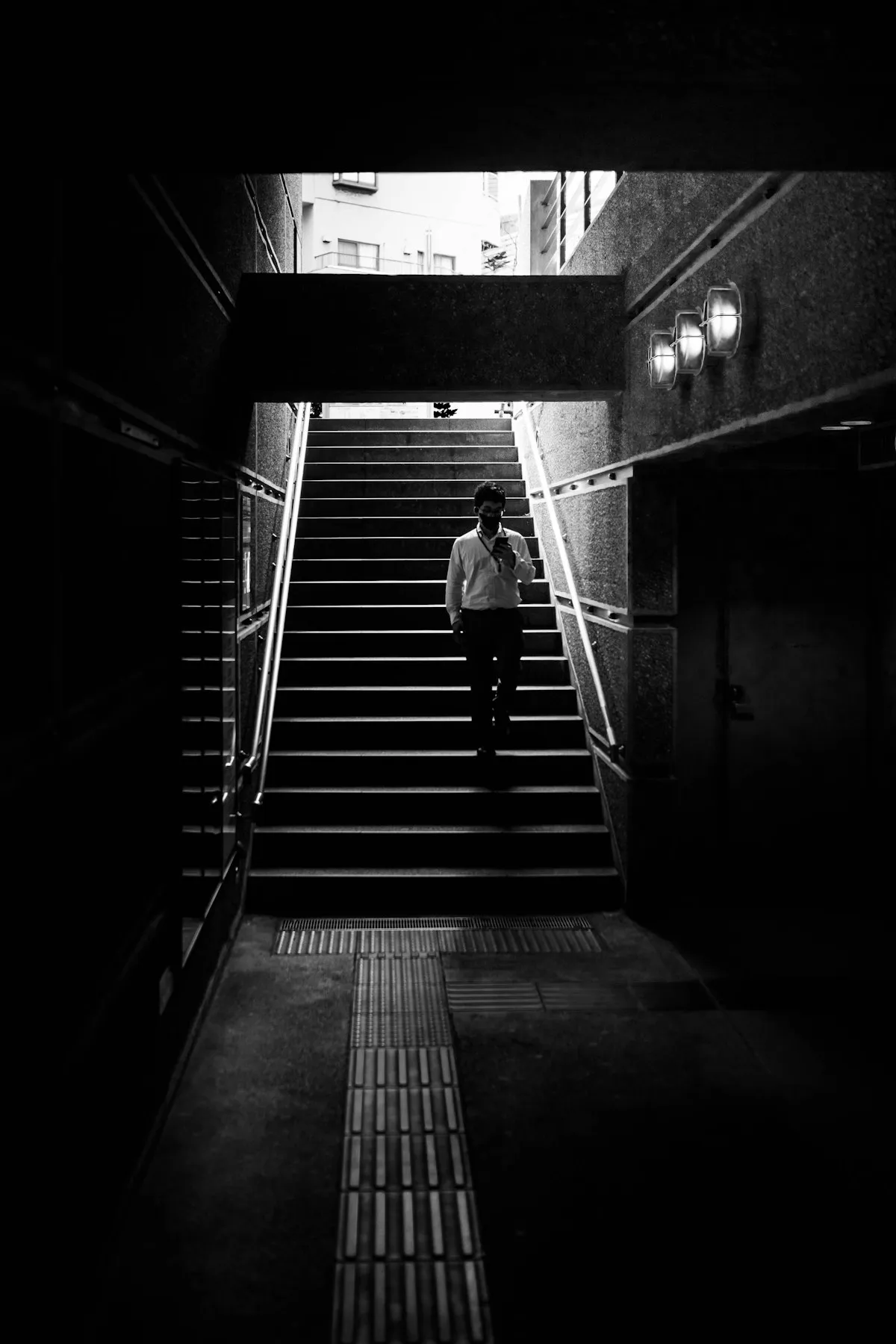麻布十番駅の階段を上がっていく人。モノクロ写真