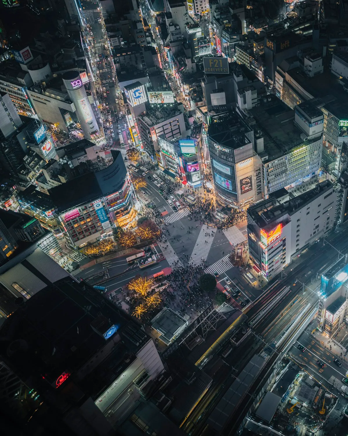 Shibuya at night seen from high above, with the scramble crossing and dense blocks of shops around it