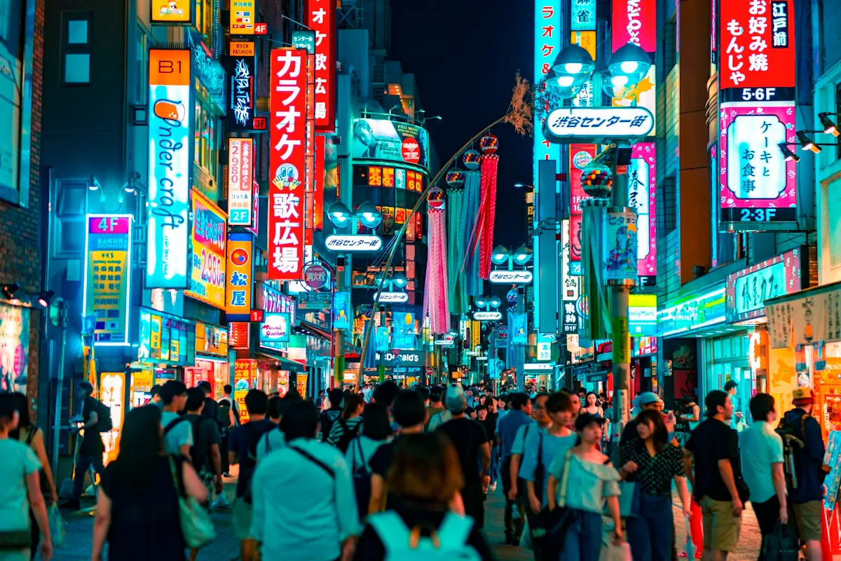 A crowded Center Gai in Shibuya at night under rows of neon signs