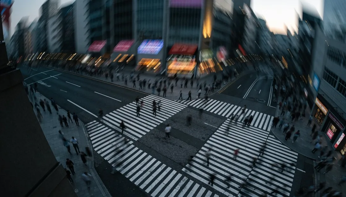 An aerial view of the Shibuya scramble crossing at dusk with crowds blurred in motion