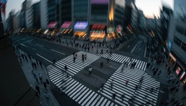 An aerial view of the Shibuya scramble crossing at dusk with crowds blurred in motion