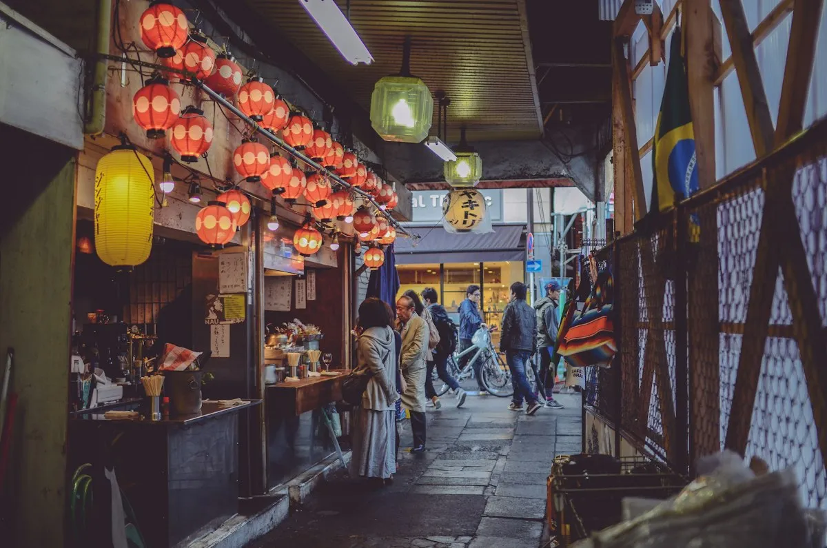 Red paper lanterns over a small food counter in a covered alley in Shimokitazawa