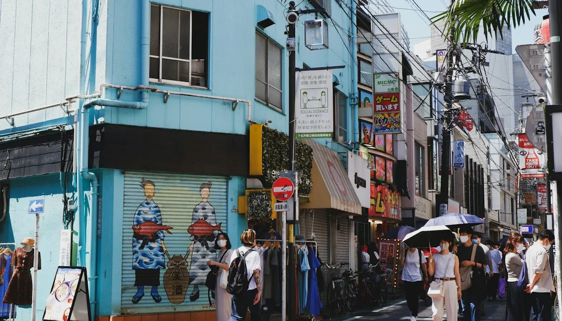 A busy shopping street in Shimokitazawa lined with shops and murals