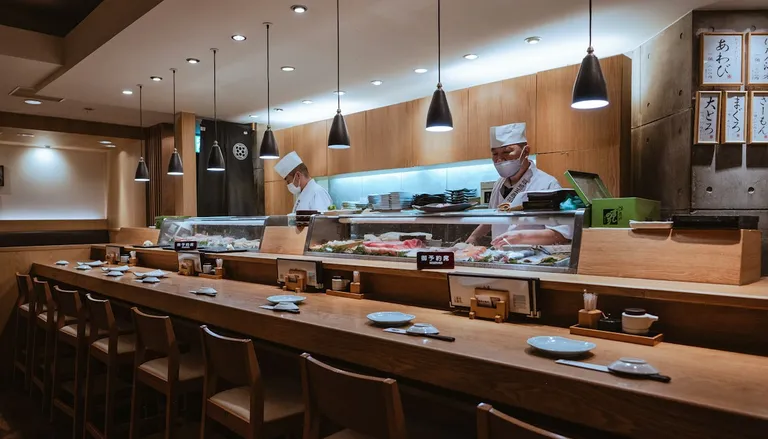A quiet sushi counter with chefs preparing food behind the glass case