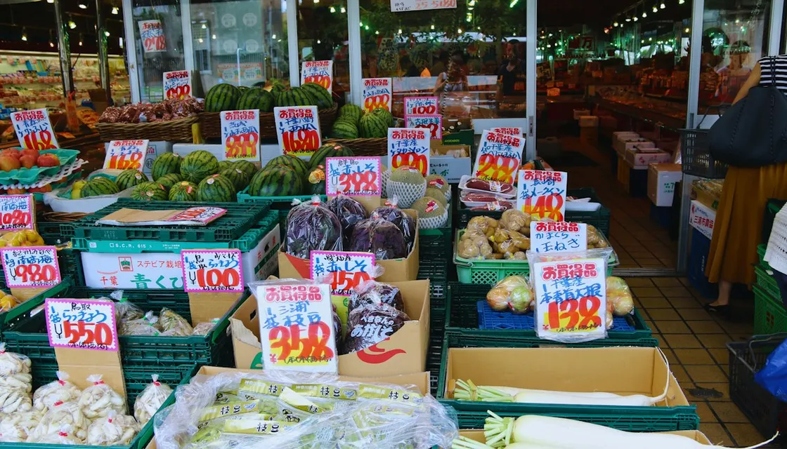 手書きの値札が付いた野菜や果物が並ぶ、日本の青果売り場