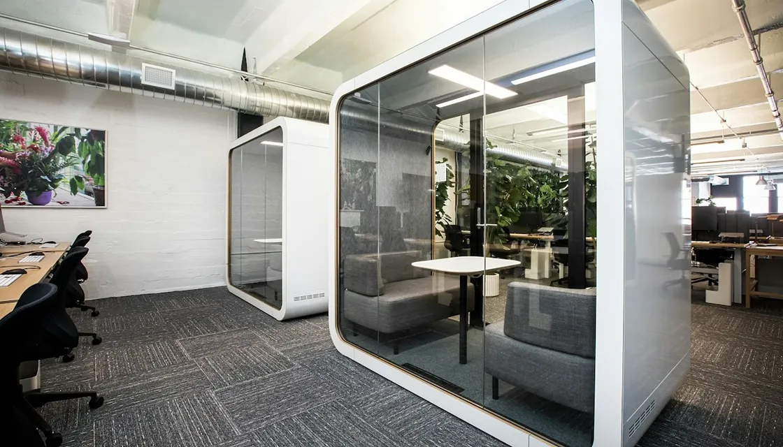 A glass-walled private booth in an open-plan office