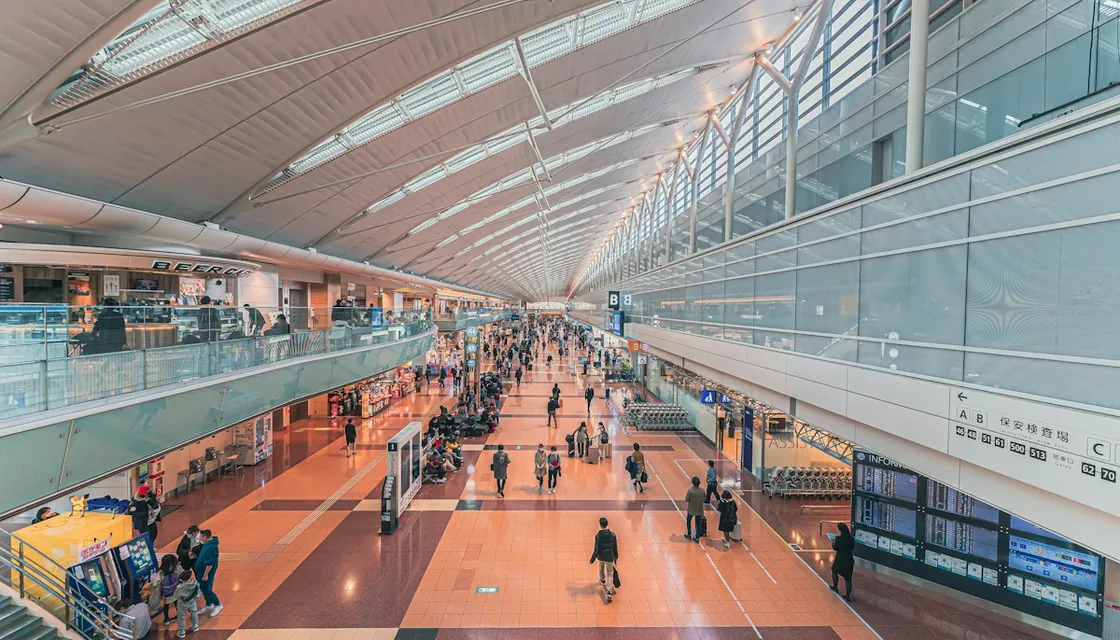 Travelers walking through the bright departure hall at Haneda Airport