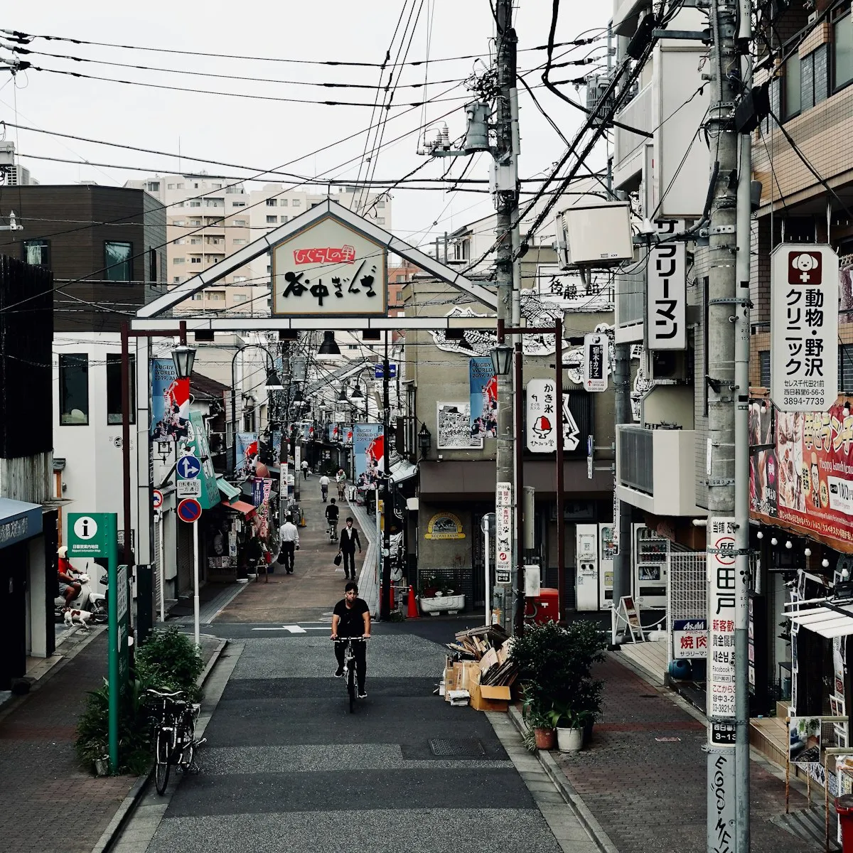 谷中銀座商店街の入口アーチと、こちらへ向かってくる自転車