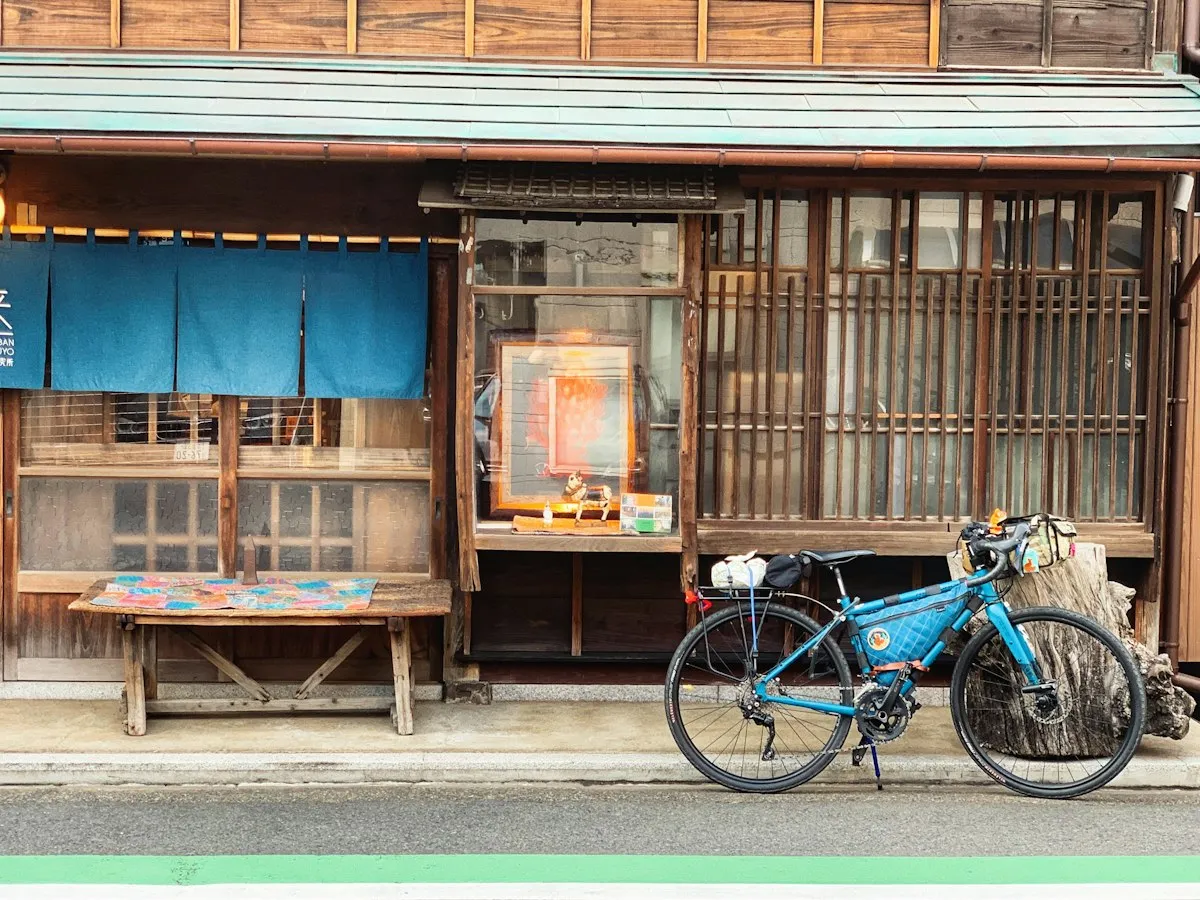 青いのれんと縁台のある、谷中の古い木造の店先。前に自転車が停まっている