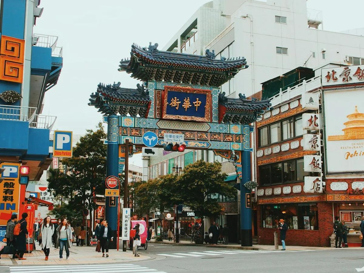 A Chinese-style gate at an entrance to Yokohama Chinatown, with restaurants and people walking around it