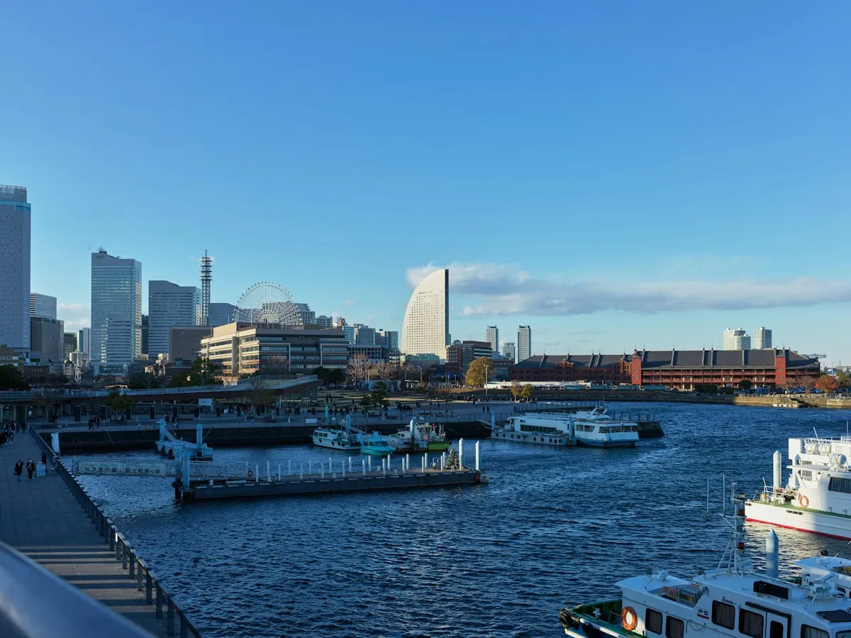Yokohama harbor on a clear day, with the Minato Mirai towers, a Ferris wheel and the Red Brick Warehouses across the water